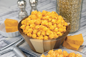 Cheesy Cheddar Poppin Popcorn in bowl on counter with ingredients